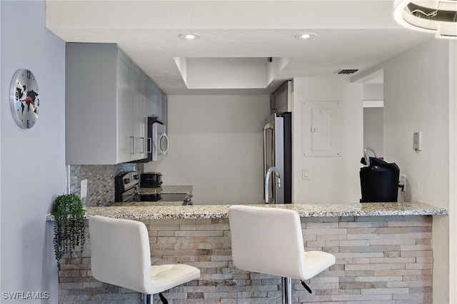 kitchen with kitchen peninsula, light stone counters, and stainless steel appliances