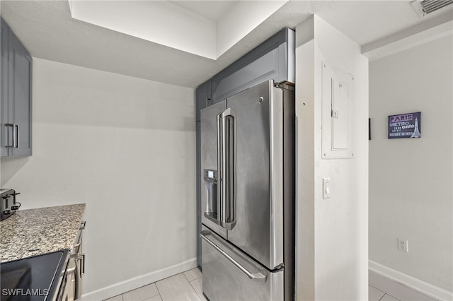 kitchen featuring high quality fridge, stone counters, light tile patterned floors, and range