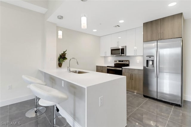 kitchen with white cabinetry, sink, tile patterned flooring, decorative light fixtures, and appliances with stainless steel finishes