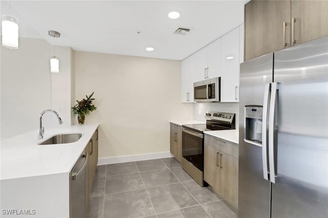 kitchen with appliances with stainless steel finishes, backsplash, sink, pendant lighting, and white cabinetry