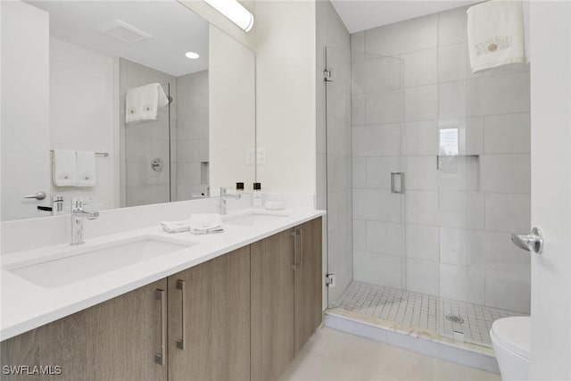 bathroom featuring tile patterned floors, vanity, toilet, and a shower with shower door