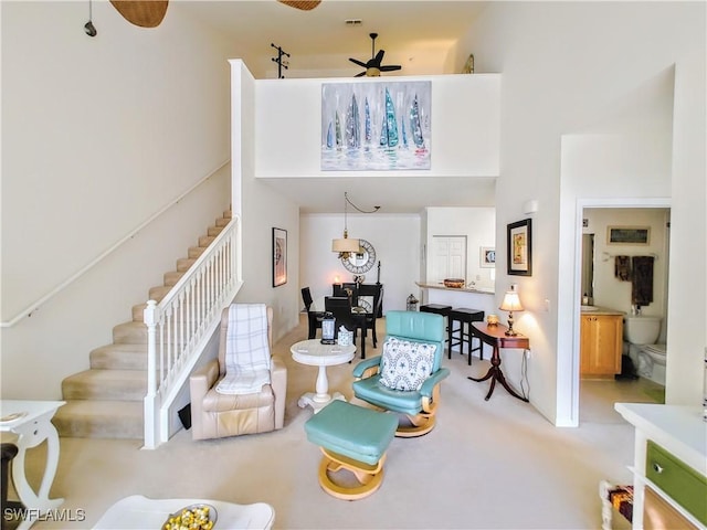 living room featuring ceiling fan, a towering ceiling, and carpet floors