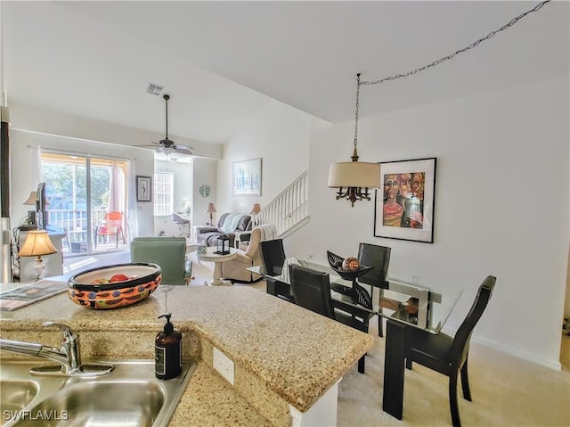 kitchen with ceiling fan, sink, hanging light fixtures, vaulted ceiling, and light carpet