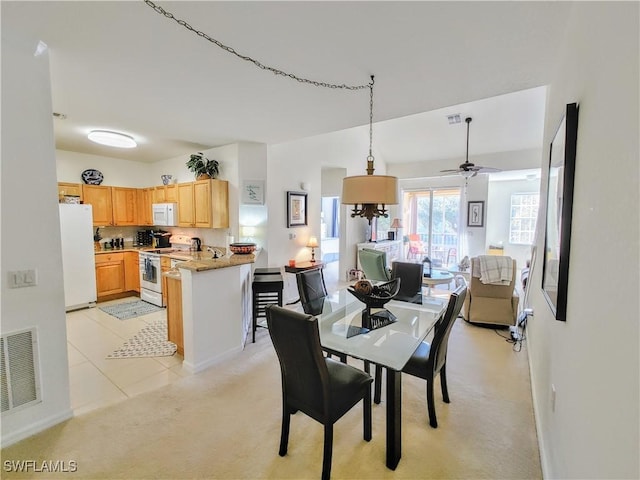 carpeted dining space with ceiling fan