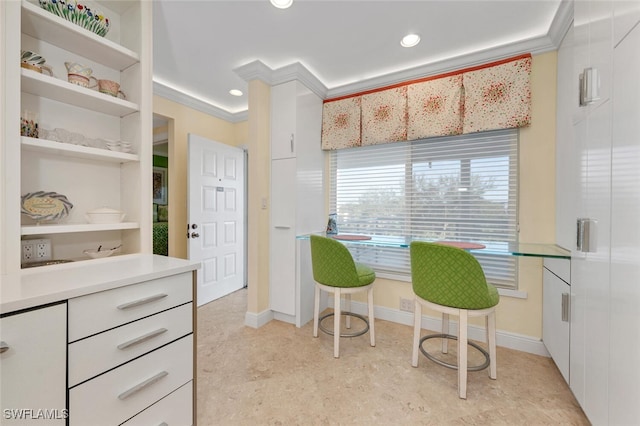 kitchen with built in shelves, white cabinetry, and ornamental molding