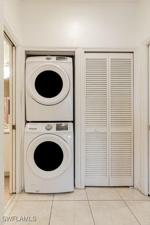 laundry room featuring stacked washer / drying machine and light tile patterned floors