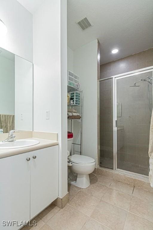 bathroom with tile patterned flooring, vanity, toilet, and an enclosed shower