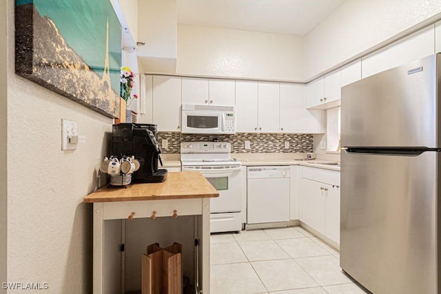 kitchen featuring white cabinetry, wood counters, tasteful backsplash, white appliances, and light tile patterned floors