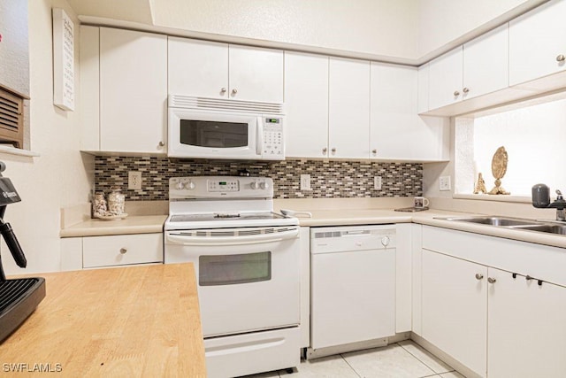 kitchen with decorative backsplash, white appliances, sink, light tile patterned floors, and white cabinetry