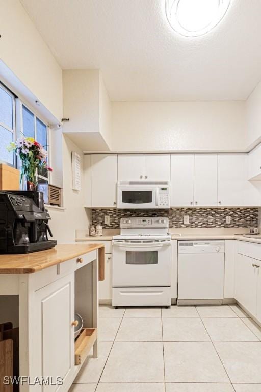 kitchen with backsplash, white appliances, light tile patterned floors, white cabinetry, and butcher block counters