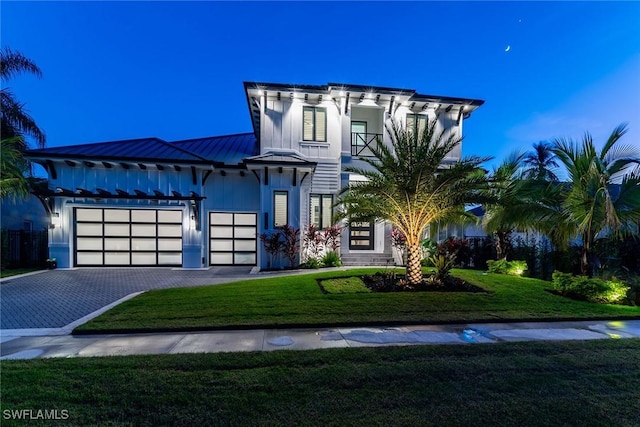 view of front of home featuring a balcony, a front yard, and a garage