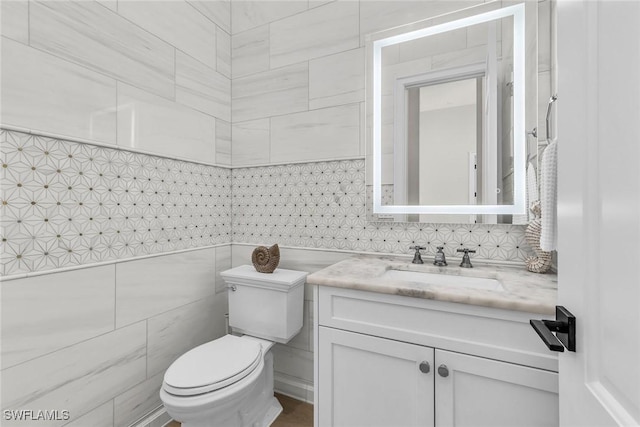 bathroom with toilet, vanity, and tile walls