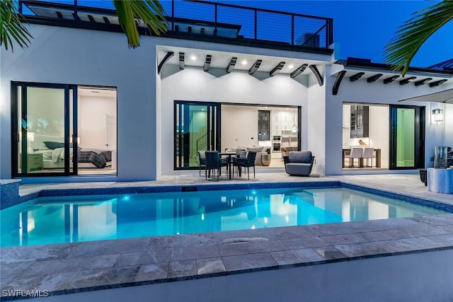 1631 Galleon Ct, Marco Island, FL 34145 - rear view of house with stucco siding, a balcony, outdoor dining area, and an outdoor pool