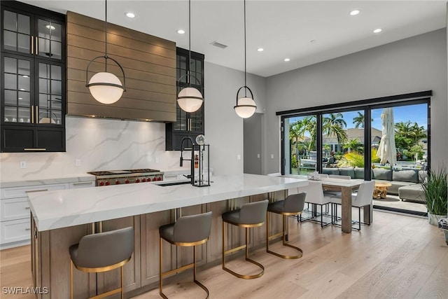 1631 Galleon Ct, Marco Island, FL 34145 - kitchen with light wood-type flooring, decorative backsplash, light stone countertops, glass insert cabinets, and recessed lighting
