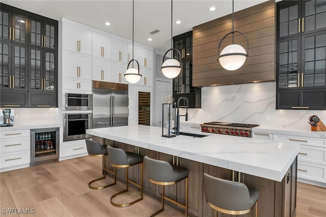 1631 Galleon Ct, Marco Island, FL 34145 - kitchen with beverage cooler, appliances with stainless steel finishes, light wood-type flooring, backsplash, and white cabinets