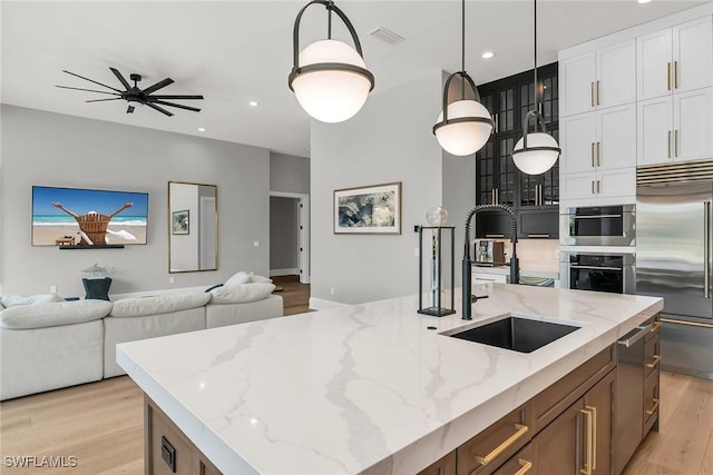 1631 Galleon Ct, Marco Island, FL 34145 - kitchen featuring stainless steel built in fridge, open floor plan, light wood-style floors, white cabinets, and decorative light fixtures