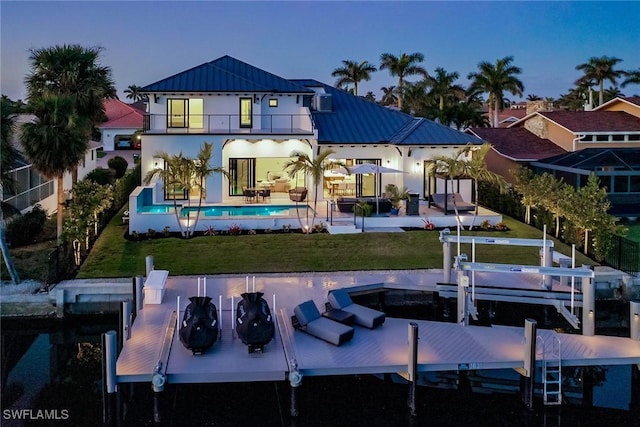 1631 Galleon Ct, Marco Island, FL 34145 - back of property with a balcony, a standing seam roof, boat lift, a metal roof, and an outdoor pool