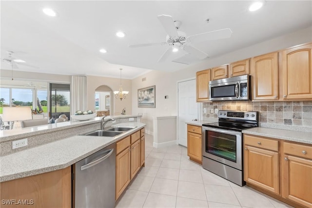 kitchen with appliances with stainless steel finishes, tasteful backsplash, a sink, and ceiling fan with notable chandelier