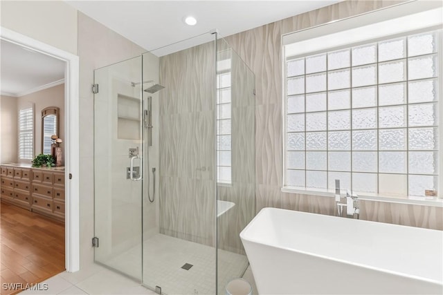 bathroom featuring recessed lighting, tile walls, ornamental molding, a soaking tub, and a stall shower