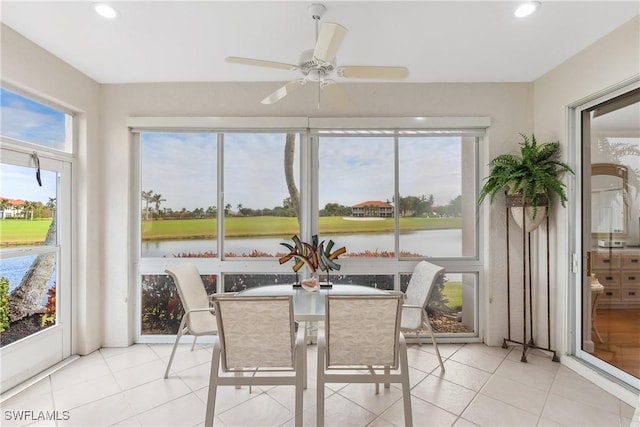 sunroom / solarium featuring a water view and a ceiling fan