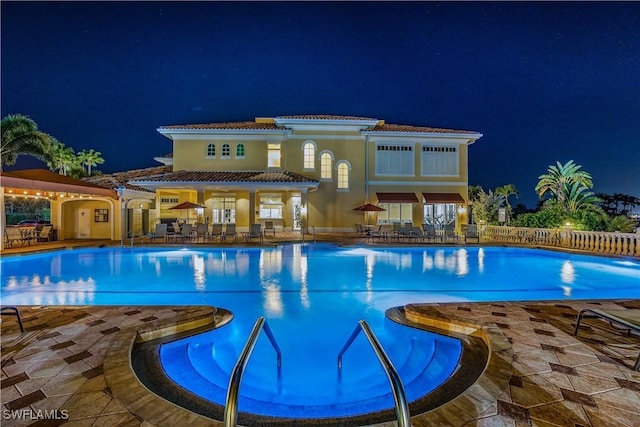 pool at twilight with a community pool and a patio