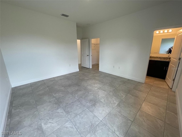 unfurnished bedroom featuring a spacious closet, connected bathroom, and a closet