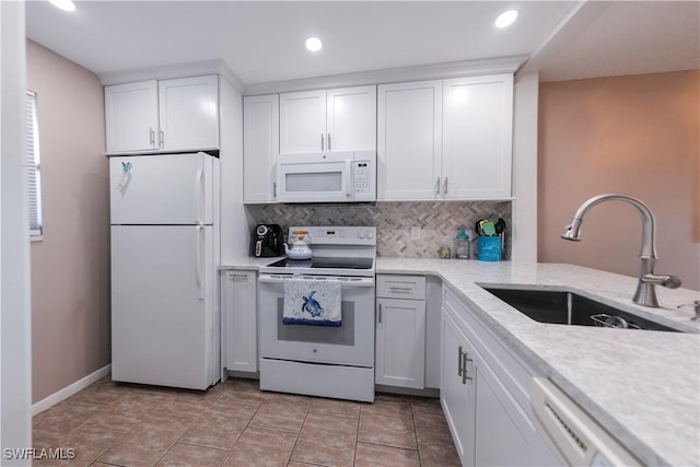 kitchen with light stone countertops, white appliances, white cabinets, tasteful backsplash, and sink