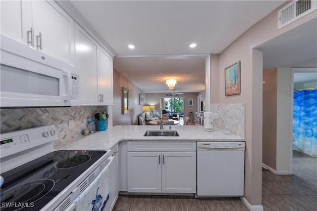 kitchen with white appliances, white cabinets, sink, backsplash, and kitchen peninsula