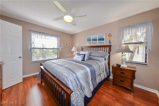 bedroom with dark wood-type flooring, ceiling fan, and a textured ceiling