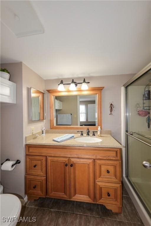 bathroom with a shower with shower door, toilet, and vanity