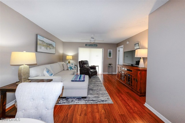 living room with ceiling fan and dark hardwood / wood-style flooring