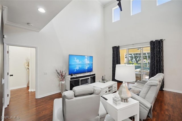 living room with a high ceiling, ornamental molding, and dark wood-type flooring