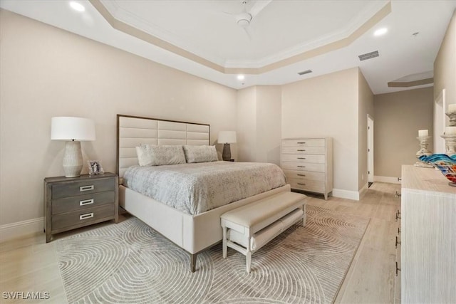 bedroom featuring ceiling fan, a raised ceiling, light wood-type flooring, and crown molding