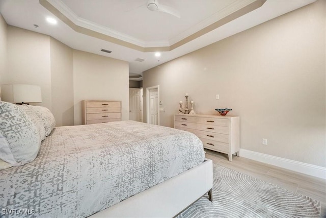 bedroom featuring light wood-type flooring, a raised ceiling, ceiling fan, and crown molding