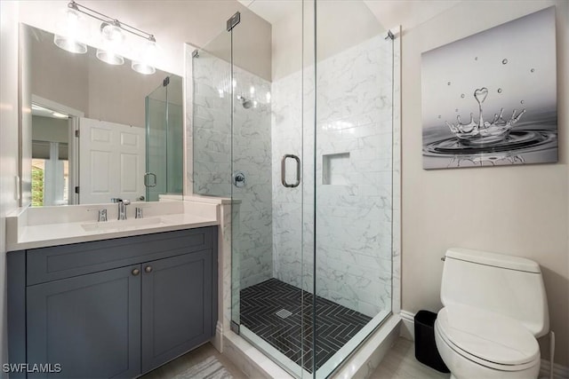 bathroom with a shower with door, vanity, and toilet