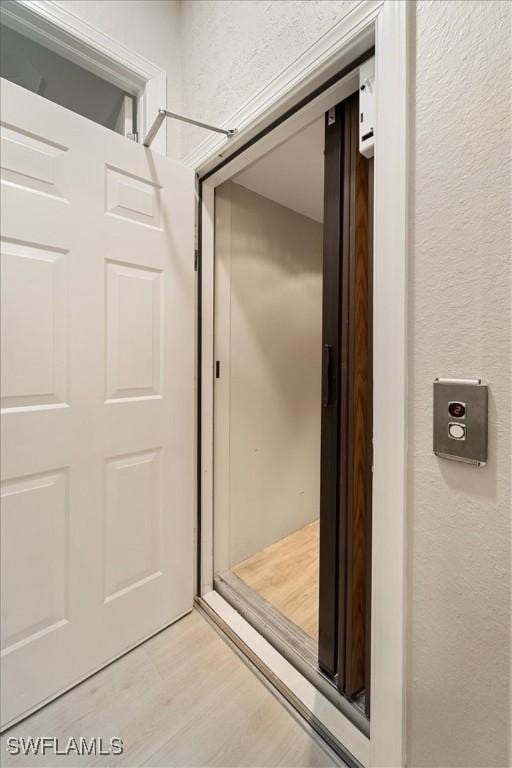 bathroom with elevator and hardwood / wood-style floors