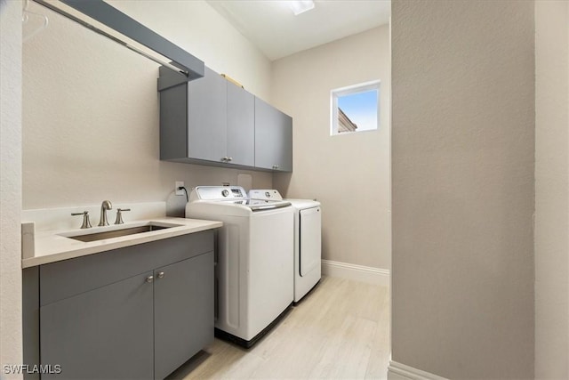 laundry room featuring light hardwood / wood-style floors, cabinets, sink, and washing machine and clothes dryer