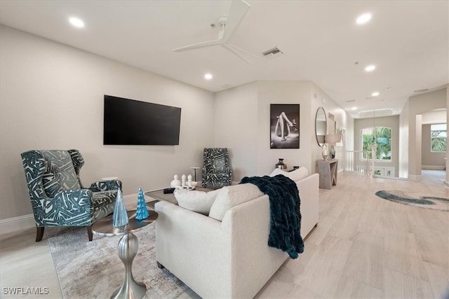 living room with ceiling fan and light hardwood / wood-style flooring