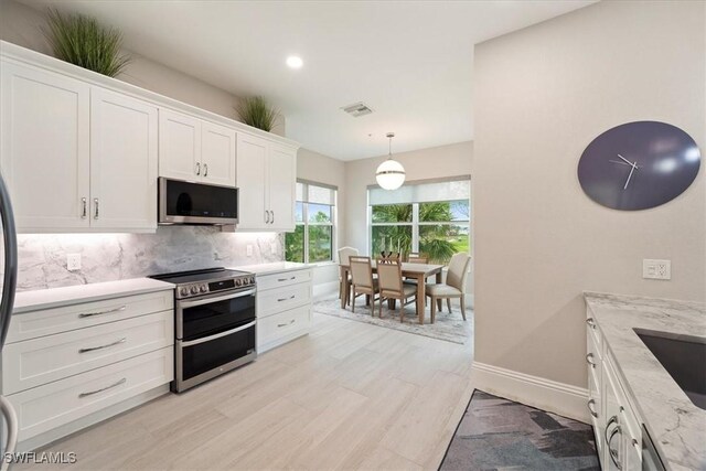 kitchen featuring pendant lighting, tasteful backsplash, light stone counters, white cabinetry, and stainless steel appliances