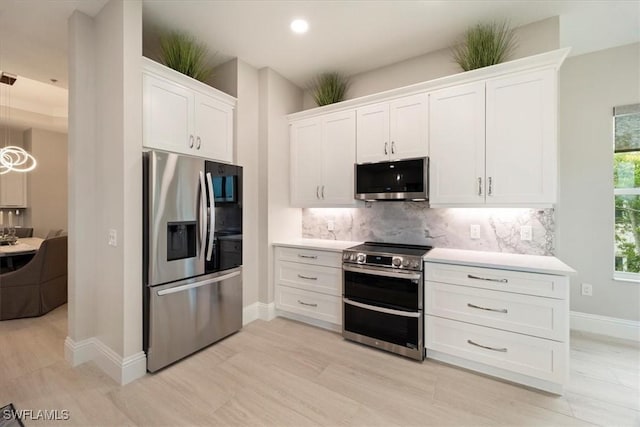 kitchen featuring stainless steel appliances, light hardwood / wood-style flooring, decorative light fixtures, decorative backsplash, and white cabinets