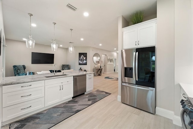 kitchen featuring pendant lighting, white cabinets, sink, light wood-type flooring, and stainless steel appliances