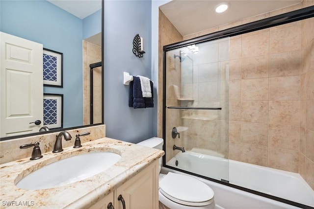 full bathroom with combined bath / shower with glass door, vanity, and toilet