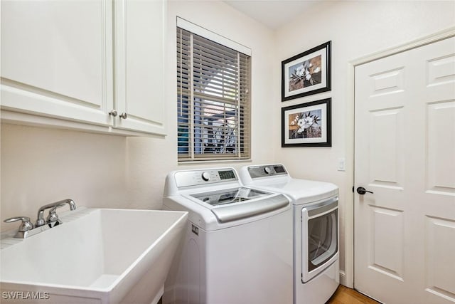 laundry room with washer and dryer, cabinets, light wood-type flooring, and sink