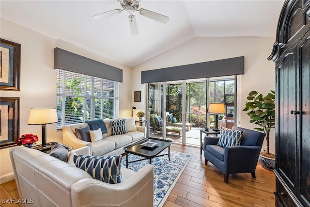 living room featuring ceiling fan, plenty of natural light, light wood-type flooring, and vaulted ceiling