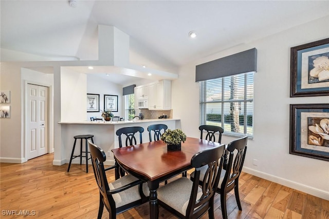 dining area with light wood-type flooring and lofted ceiling