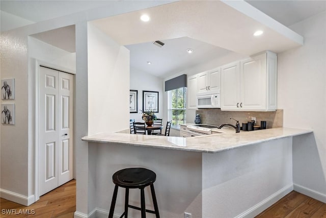 kitchen with backsplash, white cabinetry, white appliances, and kitchen peninsula