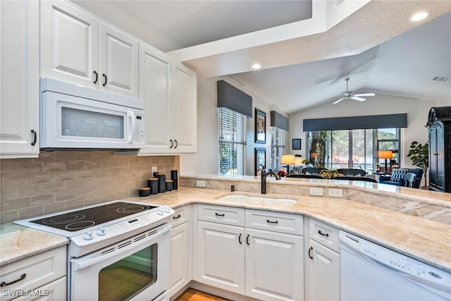 kitchen featuring kitchen peninsula, white appliances, sink, white cabinets, and lofted ceiling