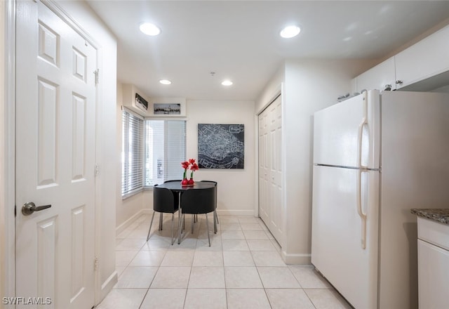 kitchen featuring white refrigerator, light tile patterned flooring, white cabinetry, and dark stone counters