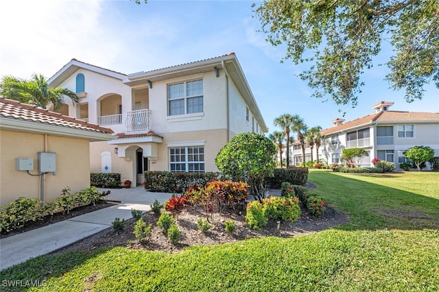 mediterranean / spanish-style house with a balcony and a front lawn