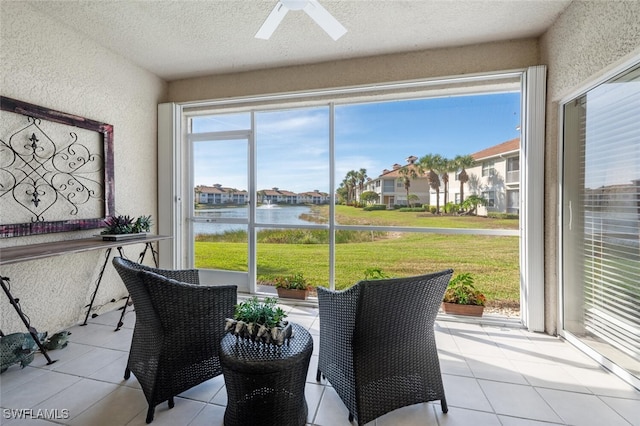 sunroom / solarium featuring a water view and ceiling fan